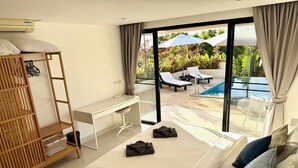 Ein Hotelzimmer mit Bett, Schreibtisch, Stuhl, Kleiderschrank und Blick auf einen Außenpool.