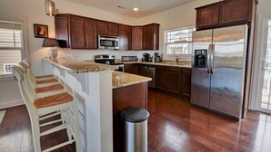 Una cocina moderna con armarios de madera oscura, electrodomésticos de acero inoxidable y encimera de granito.