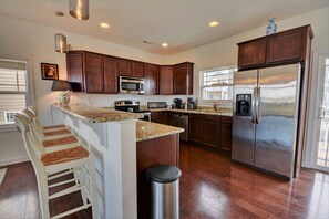 A modern kitchen with dark wood cabinets, stainless steel appliances, and a granite countertop. - Appreciate sound views at Knot Fade Away, a spacious 4-bedroom in North Topsail Beach. (North Topsail Beach)
