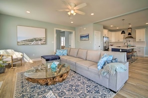 A spacious living room with a sofa, coffee table, and a view of the kitchen.