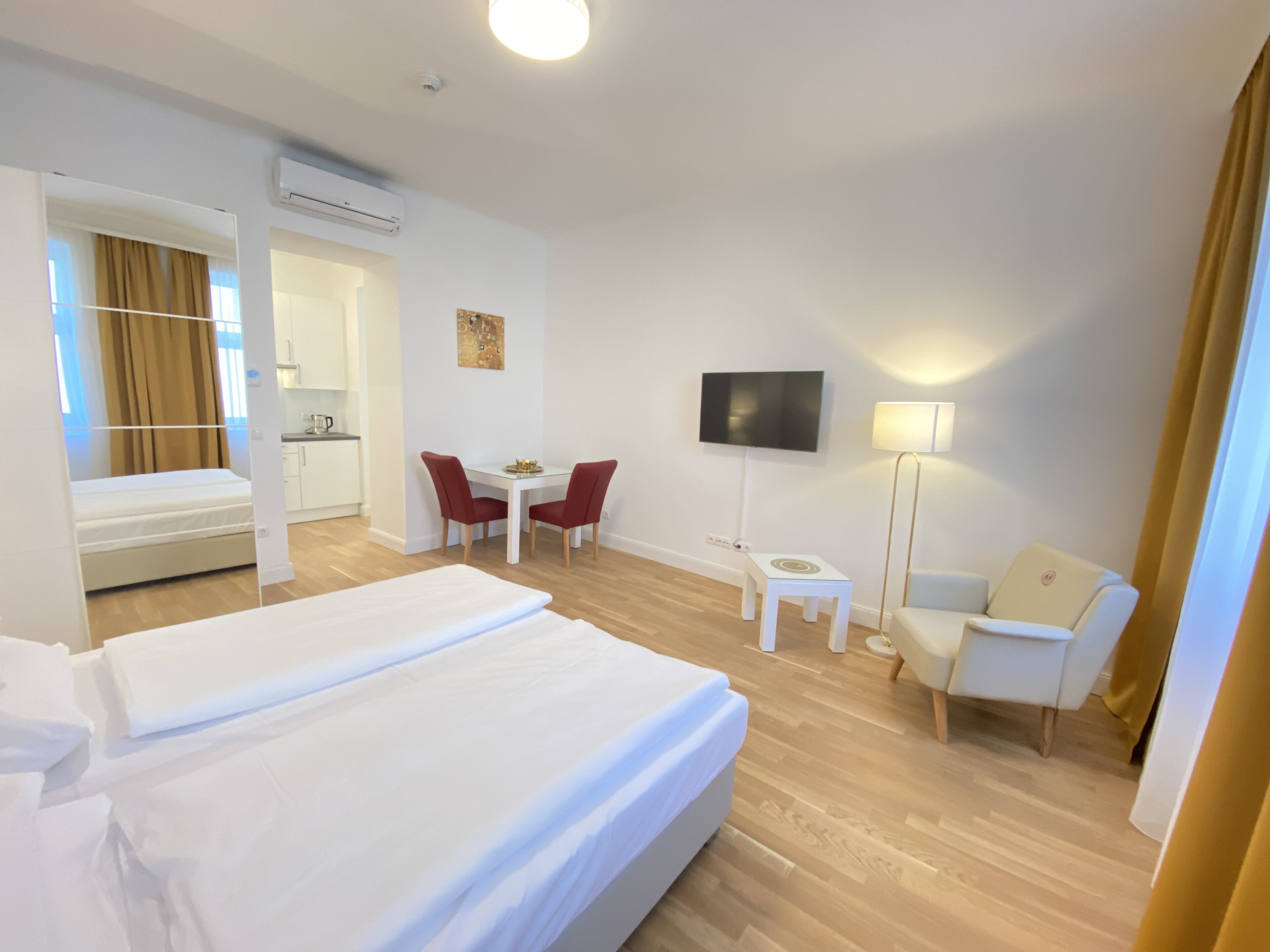 Une chambre d’hôtel avec un grand lit, un bureau avec une chaise, un téléviseur fixé au mur et une petite table avec une lampe.