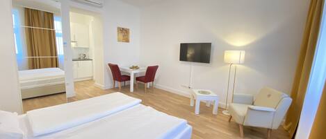 Une chambre d’hôtel avec un grand lit, un bureau avec une chaise, un téléviseur fixé au mur et une petite table avec une lampe.