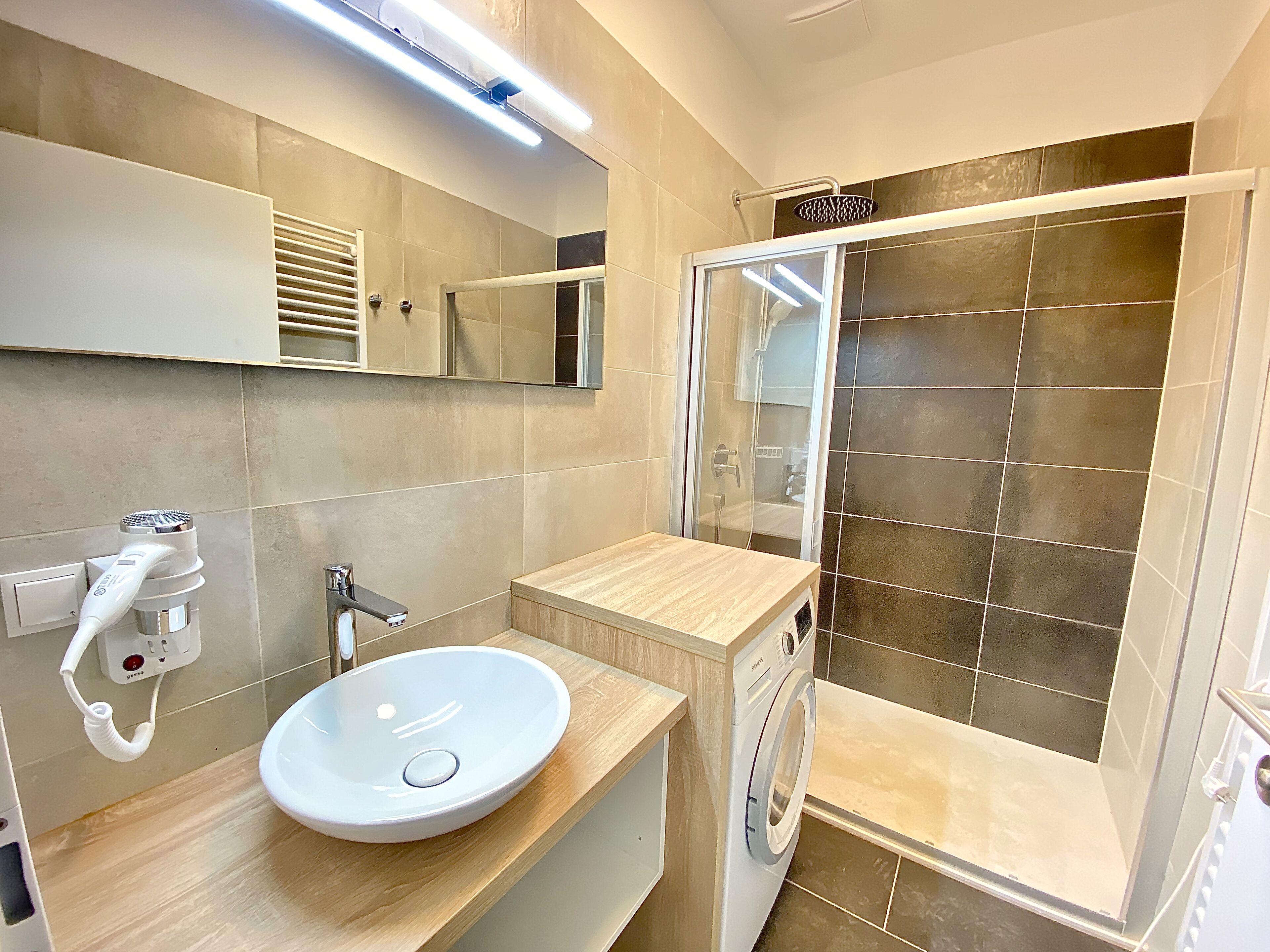 Une salle de bain moderne avec un lavabo, un miroir et une douche.