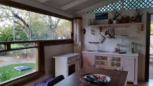 Une cuisine avec une fenêtre, un évier et une cuisinière. On y trouve une table sur laquelle est posée une assiette de légumes.