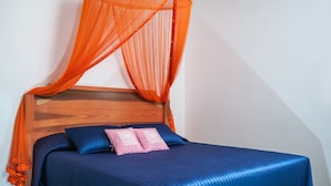 Une chambre à coucher avec une tête de lit en bois, une couvre-lit bleue et un baldaquin orange.