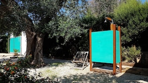 Un jardin agrémenté d’une pergola en bois, d’une petite table en bois et d’un paravent turquoise.