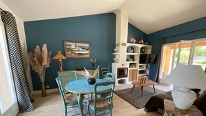 Ein Wohnzimmer mit blauer Wand, einem Esstisch mit Stühlen, einem Kamin und einem Fernseher.