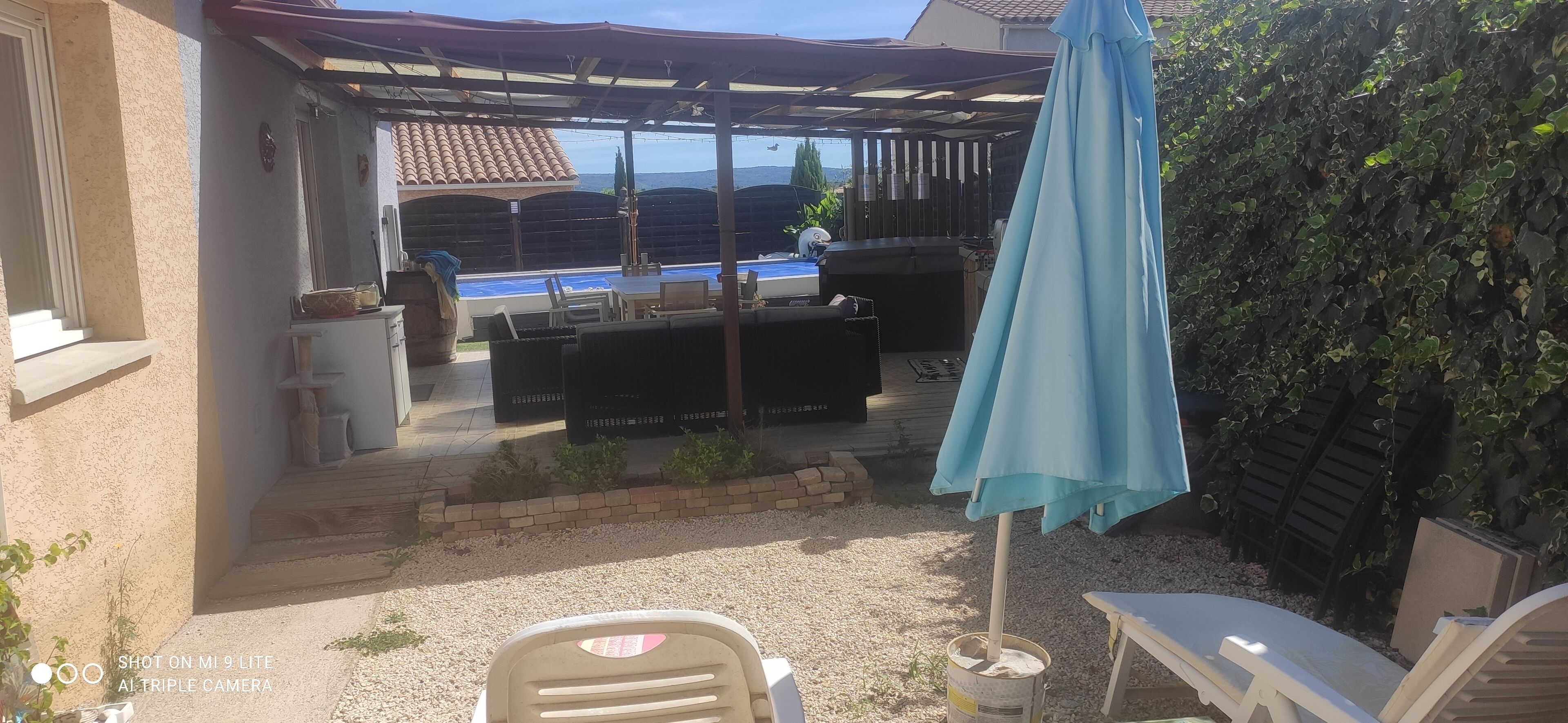 Un espace extérieur abrité comprenant un barbecue, une piscine et des sièges.