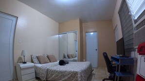 A bedroom with a bed, a desk, a chair, a lamp, a wardrobe, and a television. - Apartment Double Bed- Sleeps 2 - Free WIFI (Ponce)
