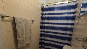 A bathroom with a toilet, sink, towel rack, and striped shower curtain. - Apartment Double Bed- Sleeps 2 - Free WIFI (Ponce)