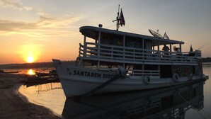 A boat named 'SANTAREM DISCO' docked at a calm river during sunset. - Gorgeous Converted Fishing Vessel in Alter do Chao (Santarém)