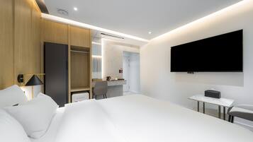 Una habitación de hotel moderna con una cama grande, un escritorio, un televisor y un vestidor.
