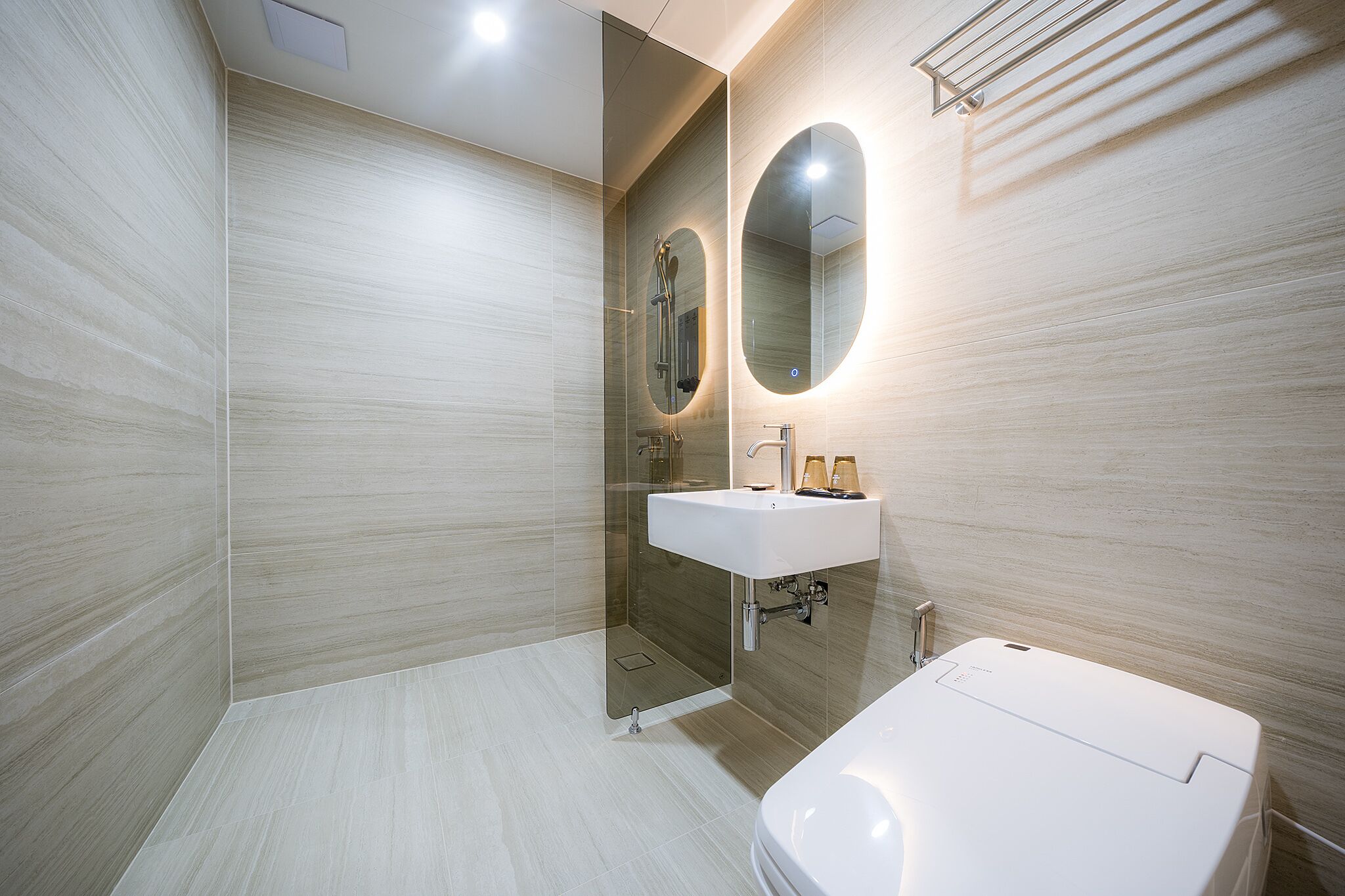 Un baño moderno con ducha de vidrio, un lavabo blanco y un espejo grande.