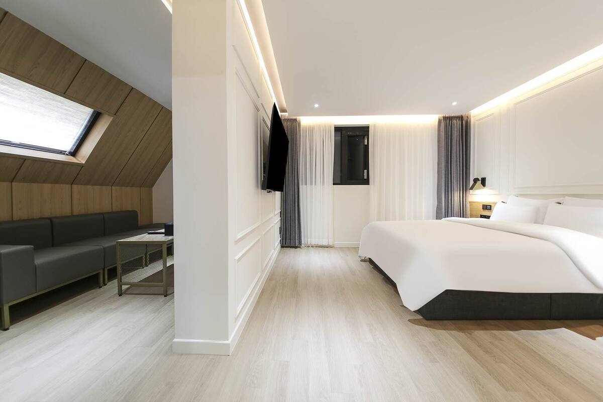 Ein modernes Hotelzimmer mit einer Couch, einem Bett, einem Fernseher und einem Schreibtisch.