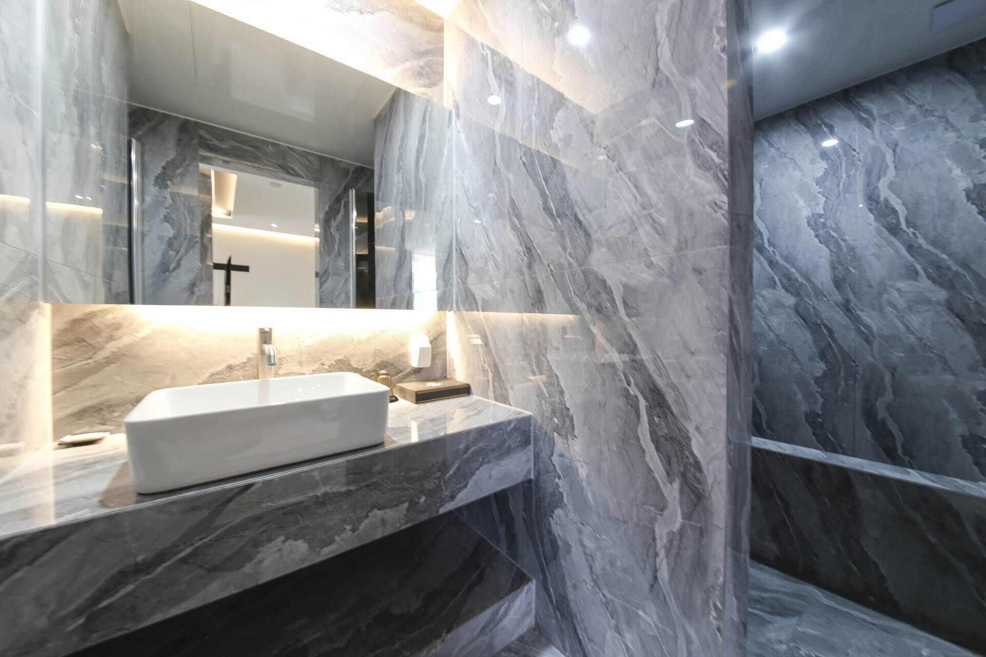 A modern bathroom with a marble sink, a large mirror, and a sleek design.