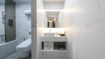 Un baño pequeño con inodoro, ducha y lavamanos con espejo.