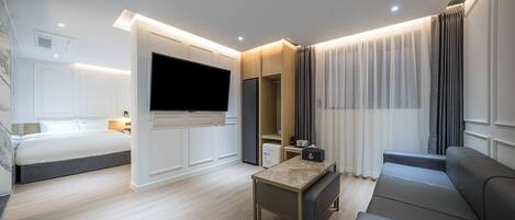Una habitación de hotel moderna con una cama, un sofá, un televisor y una mesita.