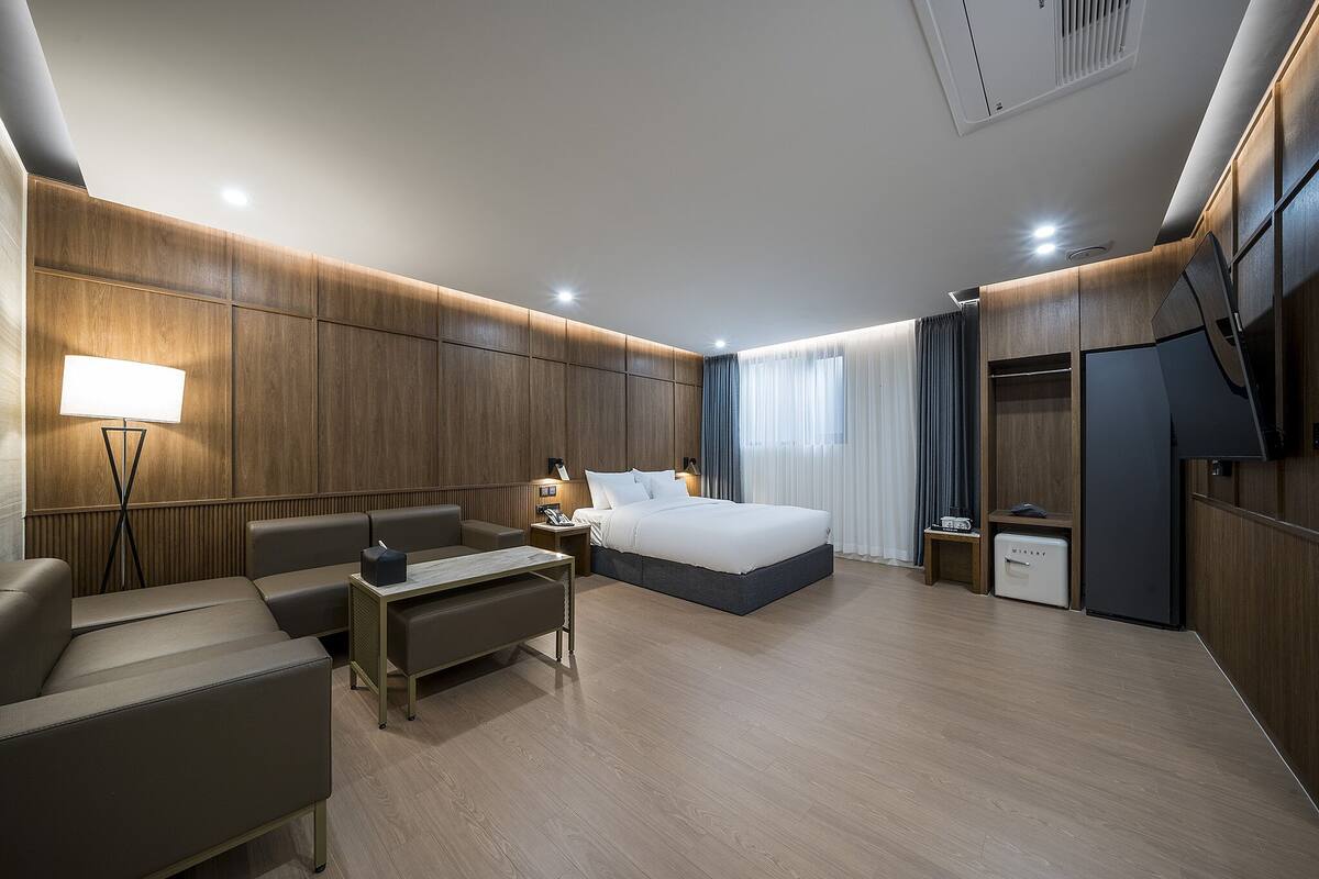 Ein modernes Hotelzimmer mit einem großen Bett, einem Schreibtisch, einem Stuhl, einem Fernseher und einem Kleiderschrank.