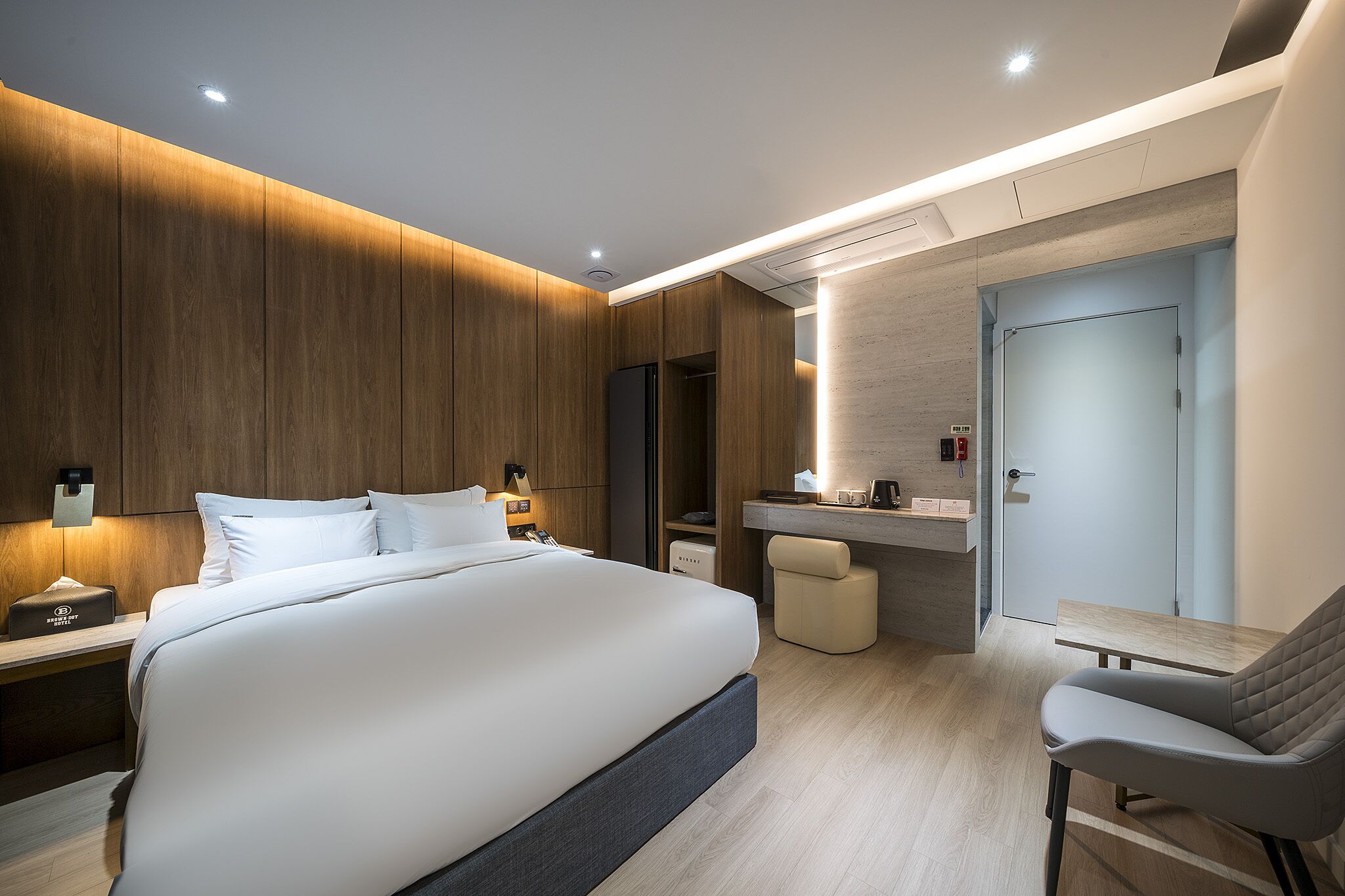 Una habitación de hotel moderna con una cama grande, mesitas de noche, un escritorio y una silla.
