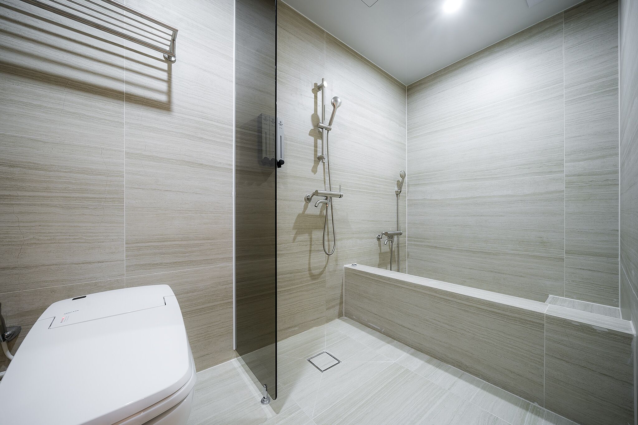 Un baño moderno con ducha envuelta en vidrio, inodoro separado y bañera.