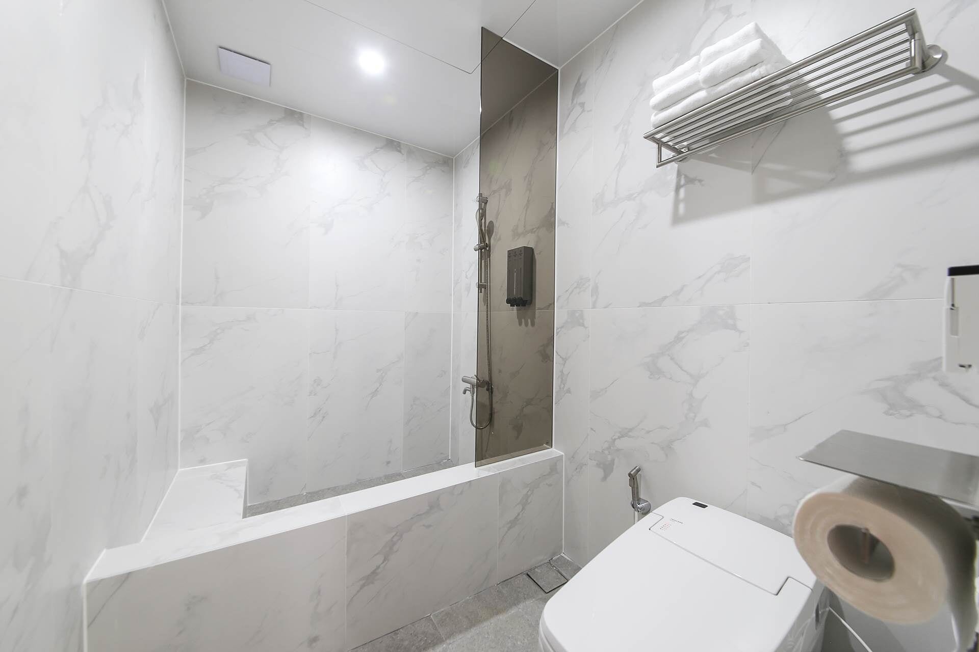 A modern bathroom with a shower, toilet, and a towel rack.