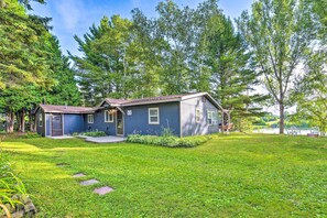 A two-story house with a blue exterior, a front porch, and a well-maintained lawn. - Riverfront Home w/ Dock ~ 6 Mi to Cheboygan! (Cheboygan)