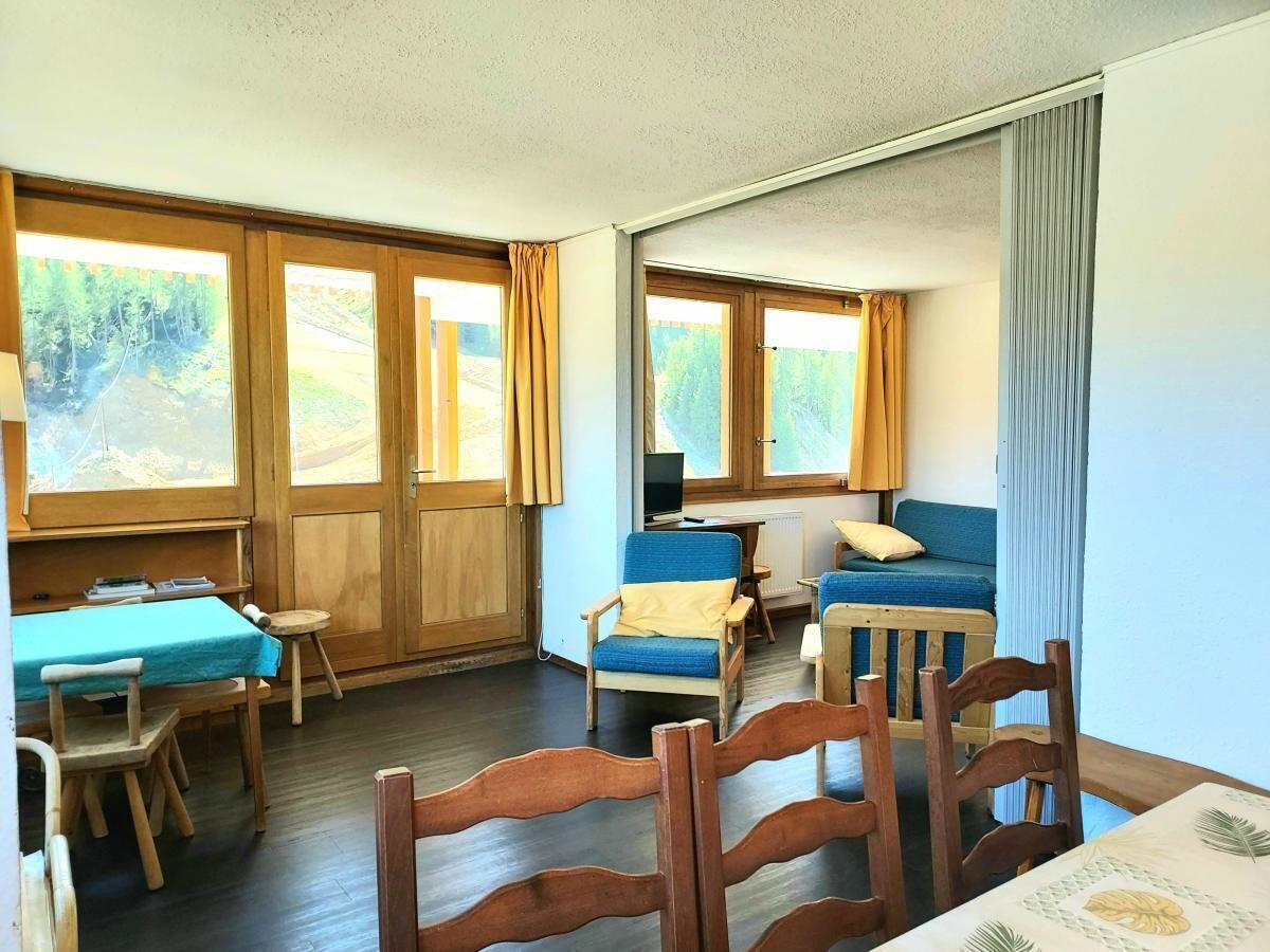 A room with a wooden table, chairs, a sofa, and a TV.