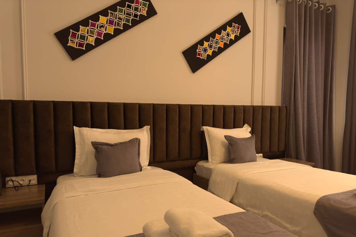 Habitación de hotel con dos camas, cabecera y una obra de arte colgada en la pared.