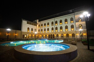 A large building with multiple arched windows and a swimming pool area with a hot tub.