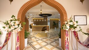 A reception area with a brick archway, a reception desk, and a patterned floor. - Rayyan Hotel Samarkand (Samarkand)