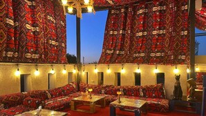 A room with patterned curtains, multiple seating areas, and tables with lamps. - Rayyan Hotel Samarkand (Samarkand)