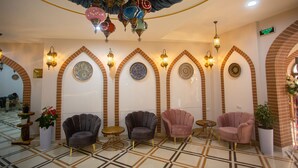 A lobby with arched brick walls, patterned floor tiles, and several seating areas with chairs and tables. - Rayyan Hotel Samarkand (Samarkand)