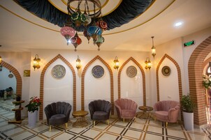 A lobby with arched brick walls, patterned floor tiles, and several seating areas with chairs and tables.