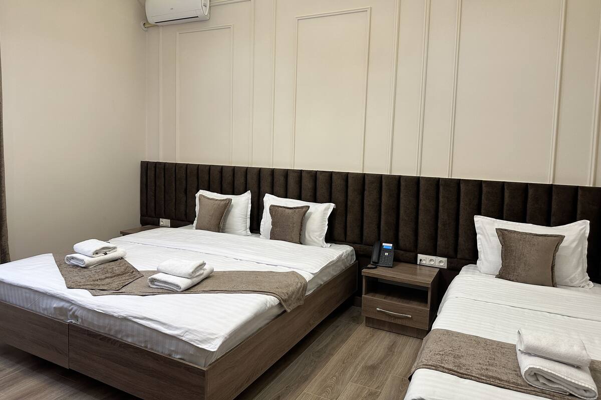 Una habitación de hotel con dos camas, una mesita de noche con teléfono y un equipo de aire acondicionado en la pared.