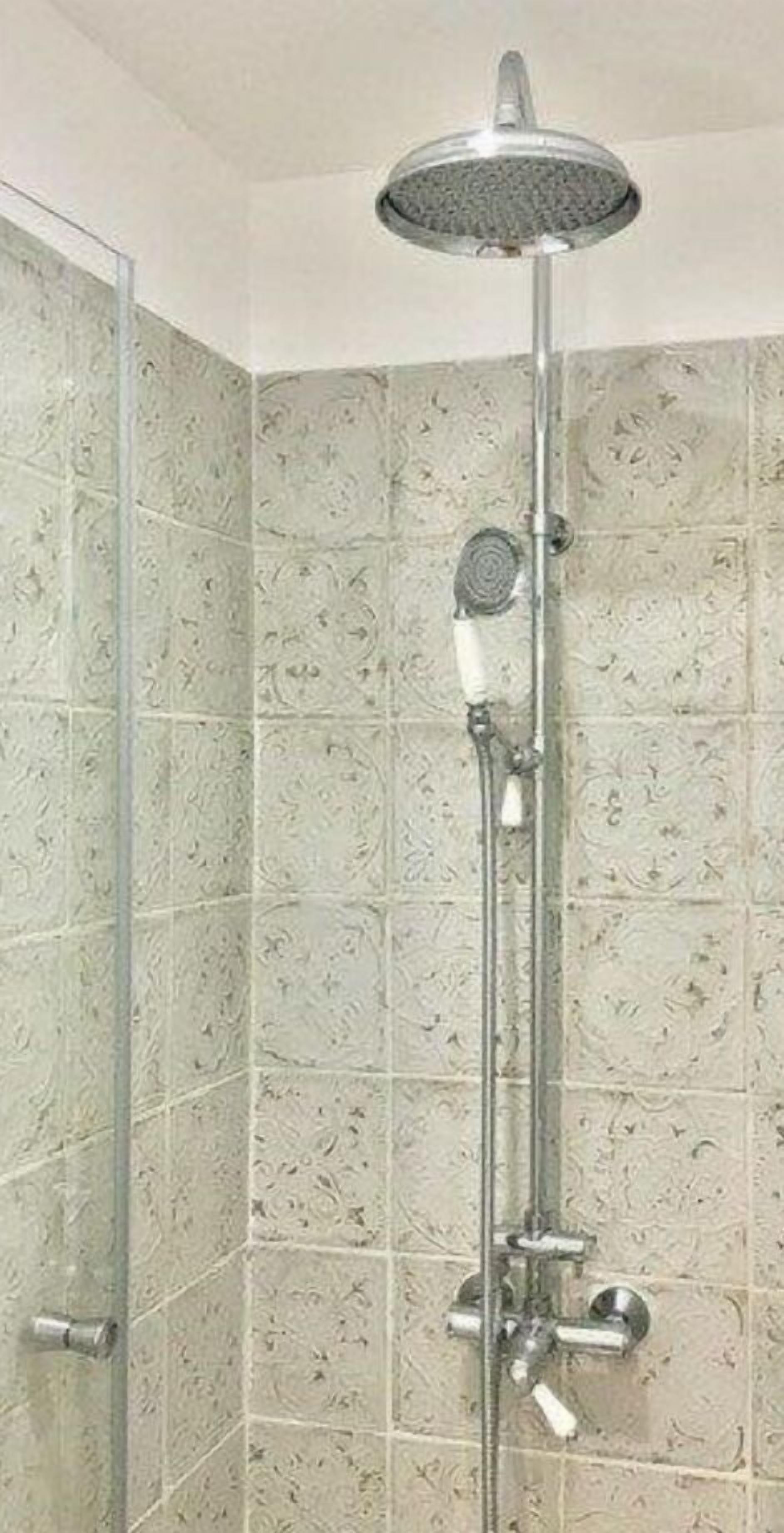 A shower with a rain showerhead, handheld showerhead, and a handheld shower attachment.
