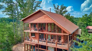 Eine mehrstöckige Holzhütte mit Balkon, umgeben von Bäumen.