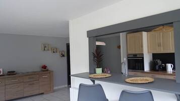 Eine moderne Küche mit grauer Arbeitsplatte, Holzschränken und einer Essecke mit zwei Stühlen.