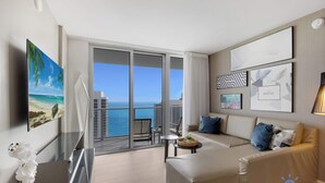 A modern hotel room with a balcony, a sofa, a TV, and artwork on the walls.