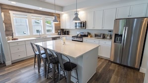 A modern kitchen with a central island, stainless steel appliances, and a large window providing natural light.