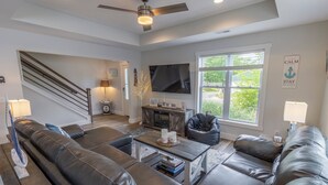 A modern living room with a large sectional sofa, a coffee table, a TV, and a staircase leading to another level.