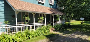 Ein Haus mit einer Veranda, weißer Brüstung und Topfpflanzen.