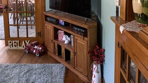 Een woonkamer met een televisie op een houten standaard, een klein autootje en een decoratieve vaas.