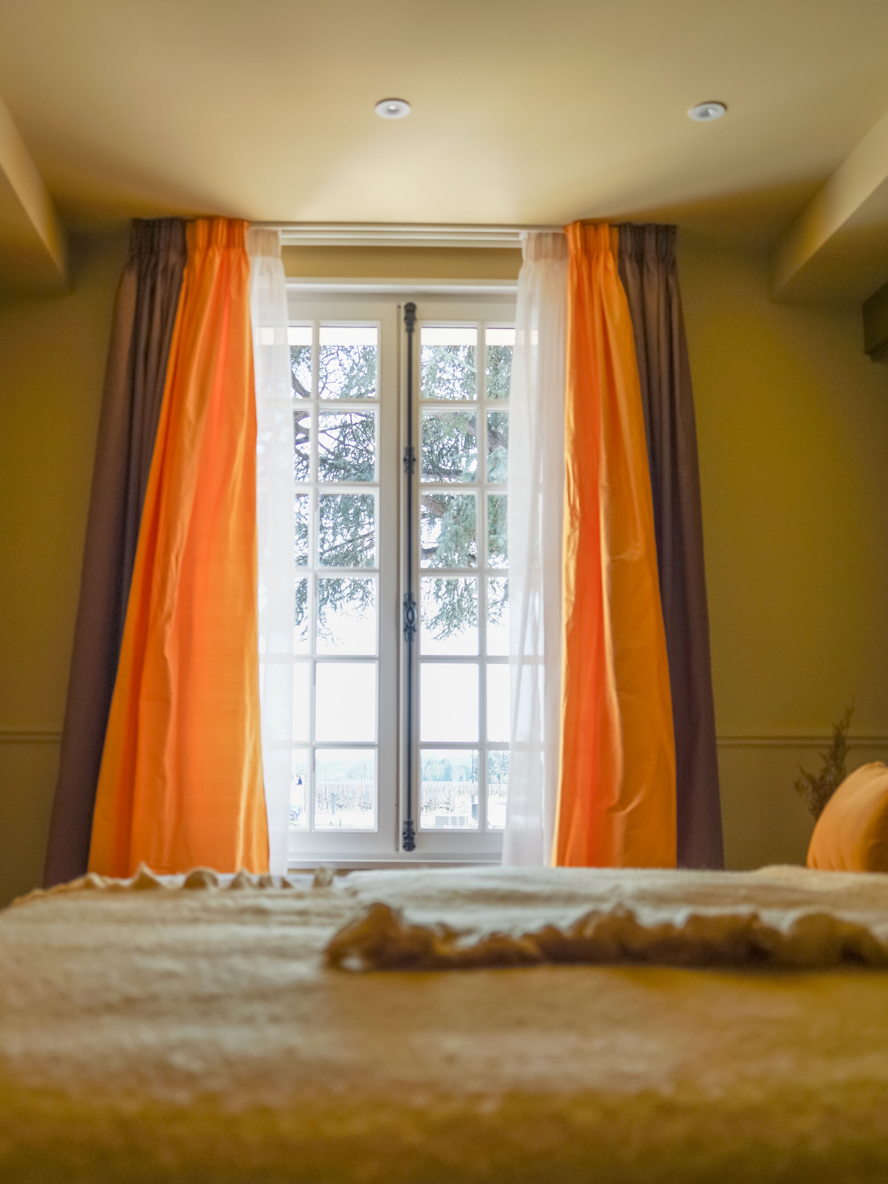 Un dormitorio con cama, ventana con cortinas y vistas a árboles.