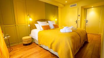 A hotel room with a bed, bedside tables, a small stool, and a door.