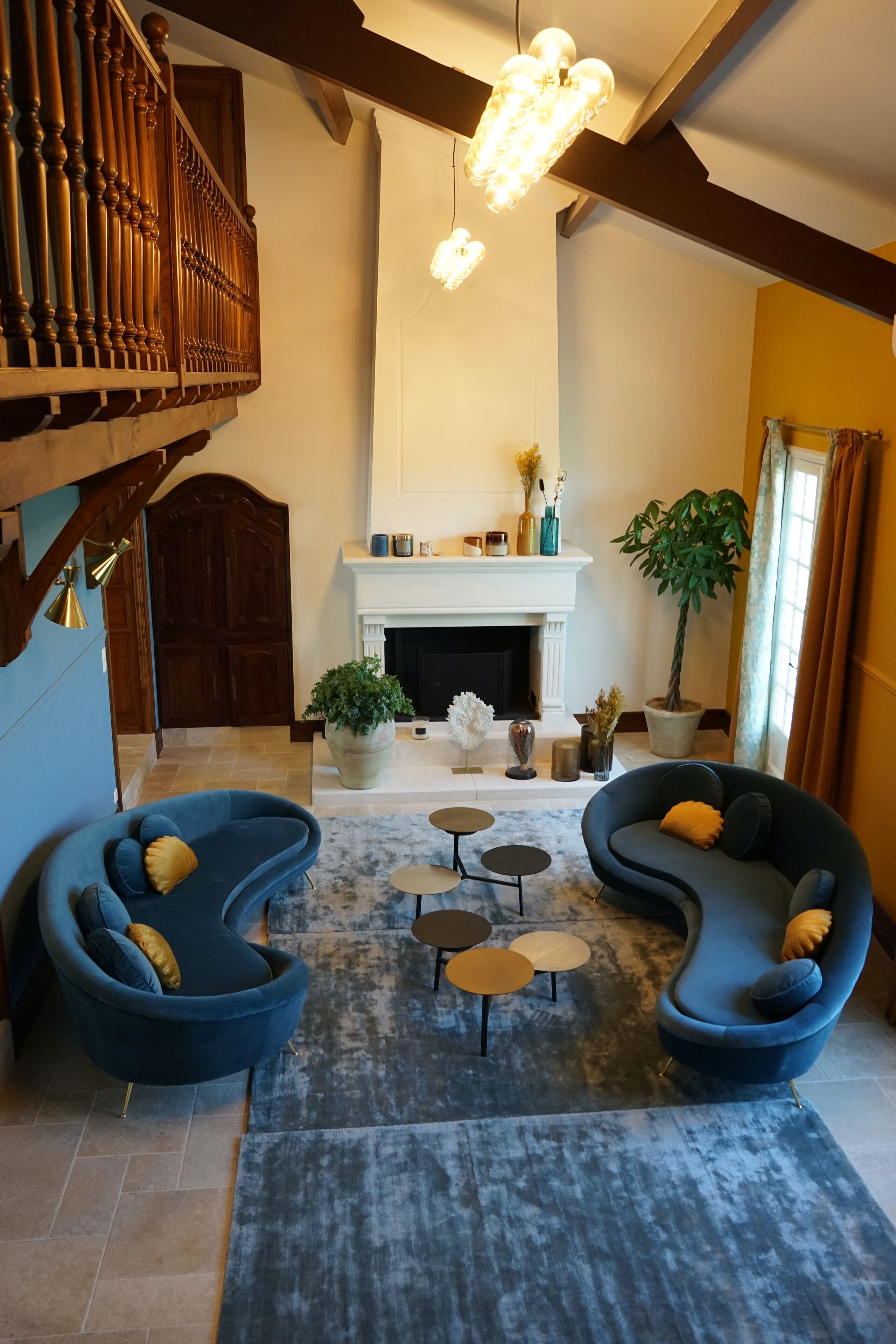 Een ruime woonkamer met een statige trap, een open haard en moderne zithoek.