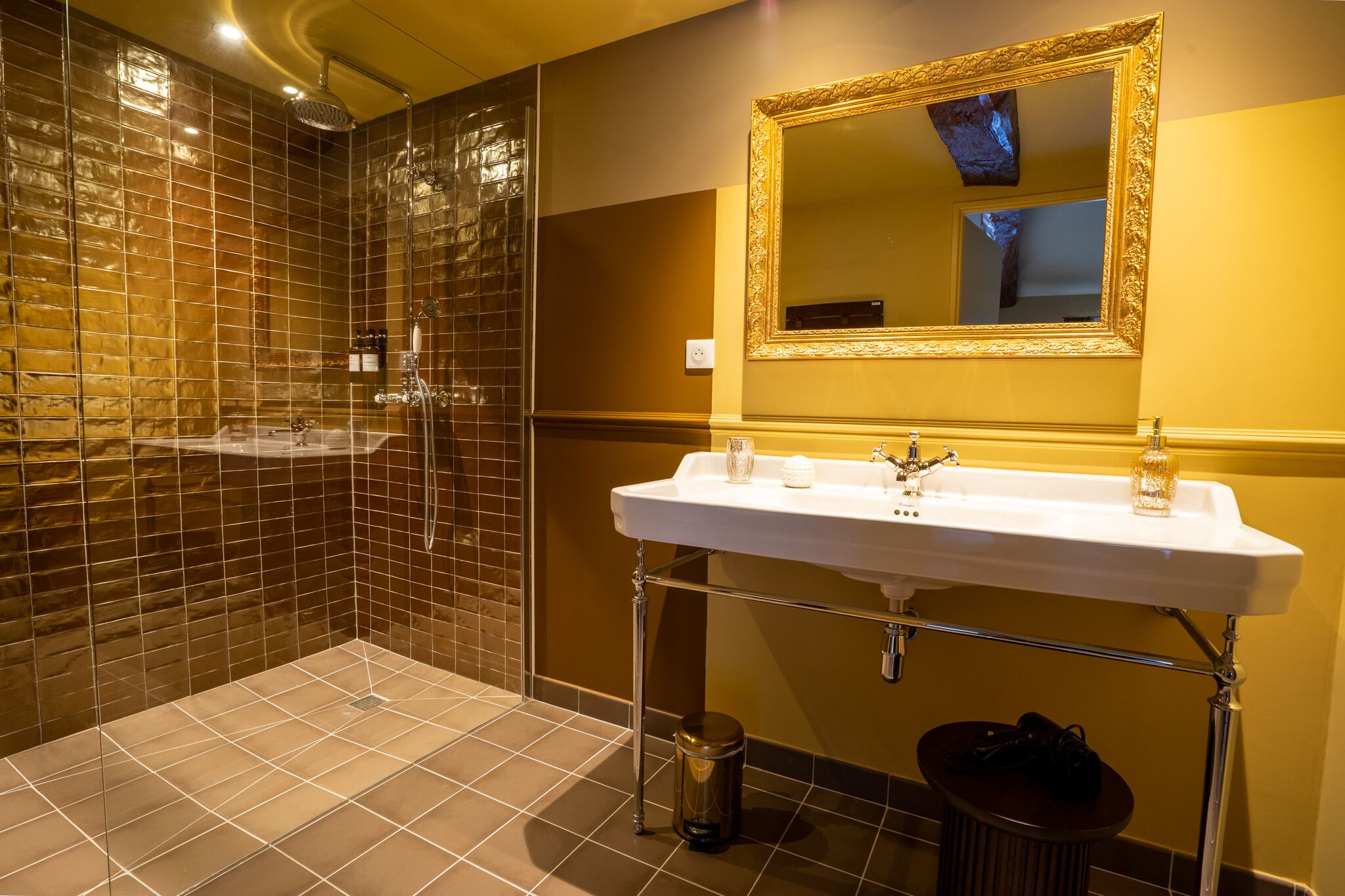 Un baño con un espejo grande, un lavamanos y una zona de ducha con paredes de azulejos.