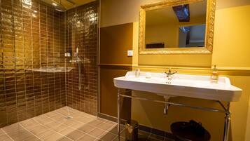 Un baño con un espejo grande, un lavamanos y una zona de ducha con paredes de azulejos.