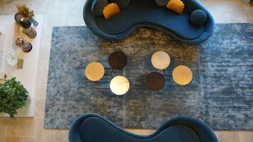 A modern living room with two blue sofas, a grey rug, and decorative round tables.