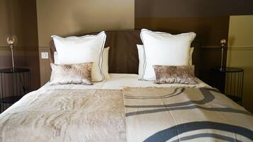 Una cama bien hecha con un edredón estampado, dos almohadas y dos mesitas de noche con lámparas.