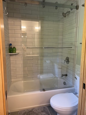 Ein modernes Badezimmer mit einer gläsernen Dusche, einer weißen Toilette und einer Duschkabine.
